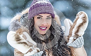 Beautiful fashion loving woman wears fur coat and furry gloves outdoors on a snowy day