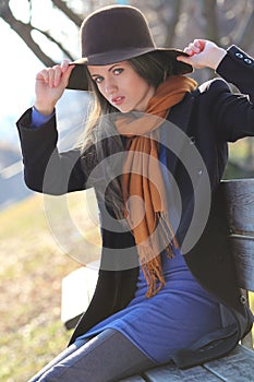 Beautiful fashion model poses on a bench