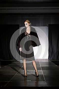 Beautiful fashion model on runway in fur coat and evening dress