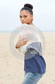 Beautiful fashion model in sweater standing at the beach alone