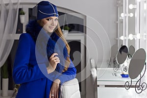 Beautiful fashion elegant girl with long hair trendy blue cap on his head from evening sitting bright makeup and painting