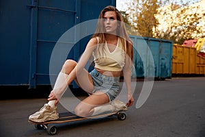 Beautiful and fashion teenage woman posing on skateboard keeping balance