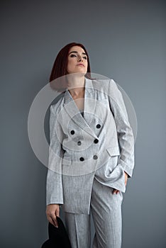 Beautiful fashion woman. Full length portrait of beautiful girl wearing light gray suit and black hat posing indoor