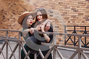 Beautiful fashion women posing. Trendy lifestyle urban portrait on city background. Girls wearing in style clothes and accessories