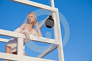 Beautiful fashionable blonde woman lifeguard on the beach by the sea