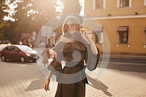 Beautiful and fashionable brunette model girl in stylish dress with naked shoulders and in the trendy sunglasses smiles and posing