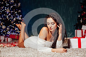 Beautiful fashionable brunette woman at the Christmas tree with gifts for the new year