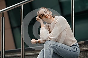 Beautiful fashionable businesswoman sitting on the stairs in front of business center. Outdoor full-length fashion