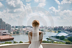 Beautiful, fashionable and elegant blond model girl with stylish hairstyle, in lace wedding dress and bridal veil looks