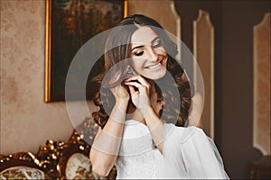 Beautiful, fashionable and elegant brunette model girl with stylish wedding hairstyle, in lace white dress puts on her