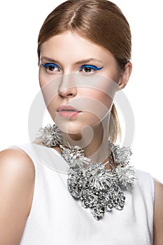 Beautiful fashionable girl with the blue arrows on eyes, smooth hair and original decoration around her neck. Model in white. Beau