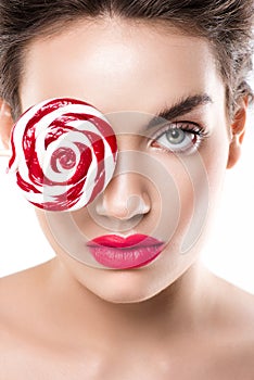 beautiful fashionable girl holding red lollipop in front of eye