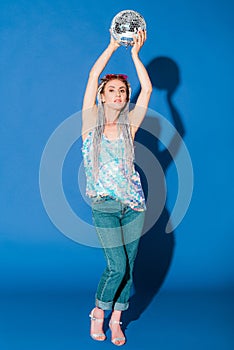 beautiful fashionable girl posing with disco ball on blue .