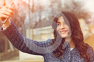 Beautiful fashionable girl taking a selfie with smartphone.