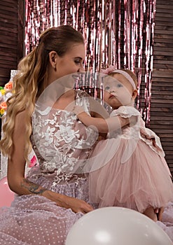 Beautiful fashionable little baby in pink dress. little princess poses like a doll with her mam