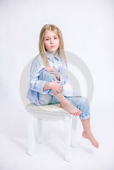 Beautiful fashionable little girl with blond hair in jeans clothes on a white background