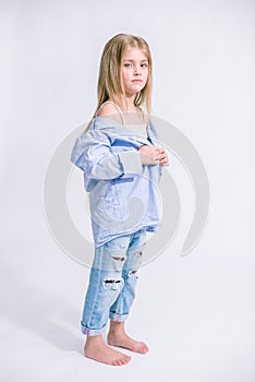 Beautiful fashionable little girl with blond hair in jeans clothes on a white background