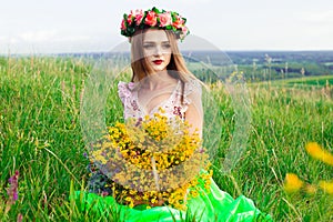 Beautiful fashionable pretty gorgeous girl in dress on the flowers field. Nice girl with wreath of flowers on her head and bouquet