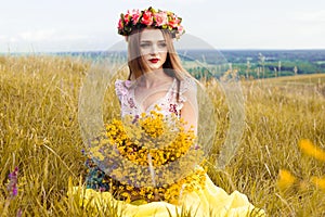 Beautiful fashionable pretty gorgeous girl in dress on the flowers field. Nice girl with wreath of flowers on her head and bouquet