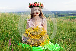 Beautiful fashionable pretty gorgeous girl in dress on the flowers field. Nice girl with wreath of flowers on her head and bouquet