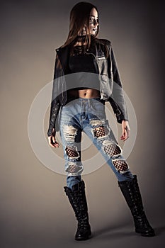 Beautiful fashionable teenager girl in leather jacket and torn jeans