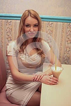 Beautiful fashionable woman girl blond   in the room in a nice dress drink a coktail and smile