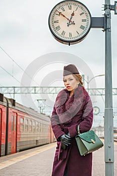 Beautiful fashionable woman on the platform waiting, gloomy autumn day
