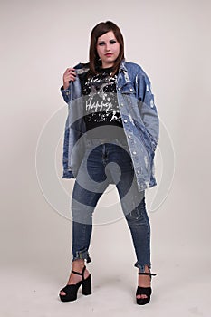 Beautiful fashionable young plump fat big oversize girl model on the studio with piercings in a black t-shirt and jeans
