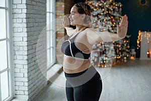 A beautiful fat woman in a sports uniform is exercising in the body to burn fat. Fitness and yoga. Sports at Christmas.