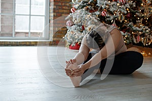 A beautiful fat woman in a sports uniform is exercising in the body to burn fat. Fitness and yoga. Sports at Christmas.