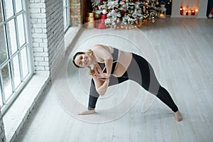 A beautiful fat woman in a sports uniform is exercising in the body to burn fat. Fitness and yoga. Sports at Christmas.