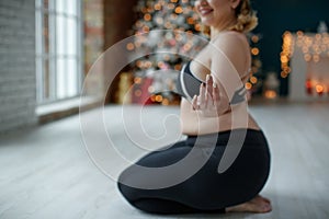 A beautiful fat woman in a sports uniform is exercising in the body to burn fat. Fitness and yoga. Sports at Christmas.