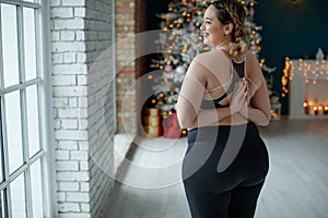 A beautiful fat woman in a sports uniform is exercising in the body to burn fat. Fitness and yoga. Sports at Christmas.