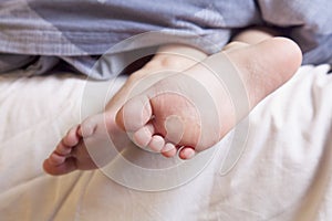 Beautiful feet of a little cute child girl lying in bed close up.  Sleep and relax concept