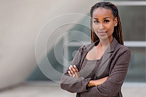 Beautiful female african american business woman CEO in a suit at the workplace, standing confidently with arms folded