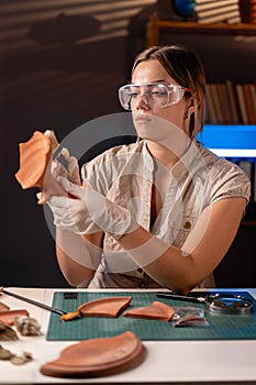 Beautiful female archeologist working late night in office