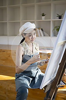 Beautiful female artist painting picture in studio.