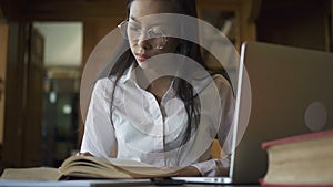 Beautiful female asian student biologist in glasses reading book