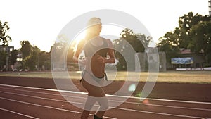 Beautiful female athlete runnung, working out in the morning on the stadium. Wearing black bikini and white sneakers