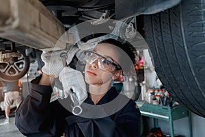 Beautiful female auto mechanic checking wheel tires in garage, car service technician woman repairing customer car at automobile