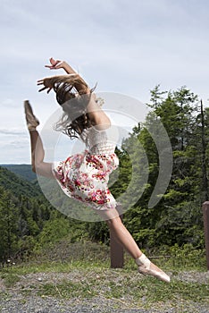 Beautiful female ballerina or dancer leaps outdoors photo