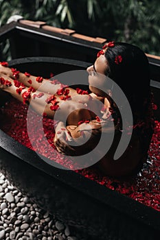 Beautiful female in bath with rose petal. Body care.