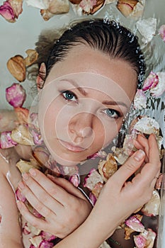 Beautiful female in bath with rose petal. hands in the frame