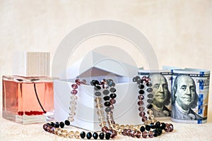 Beautiful Female Beads in White Gift Box, Eau de Toilette,  and Paper Banknotes American Dollars Lay on a White  Background