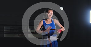 Beautiful female boxer pulls red bandages over her arms in slow motion. Steadicam shot