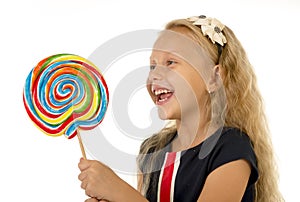 Beautiful female child with long blond hair holding huge spiral lollipop candy smiling happy