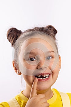 Beautiful female child with opened mouth showing missing front milk tooth with finger on bottom lip smiling excitedly on