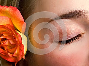 Beautiful female closed eye and rose close-up