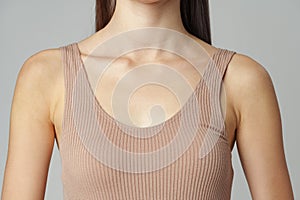 Beautiful female collarbone in cotton beige underwear over grey studio background