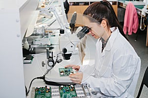 Beautiful female computer expert professional technician examining board computer in a laboratory in a factory photo